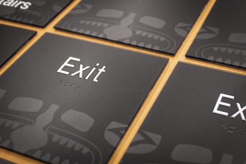 Grid of ADA-compliant Exit signs with raised white lettering and tribal-inspired background